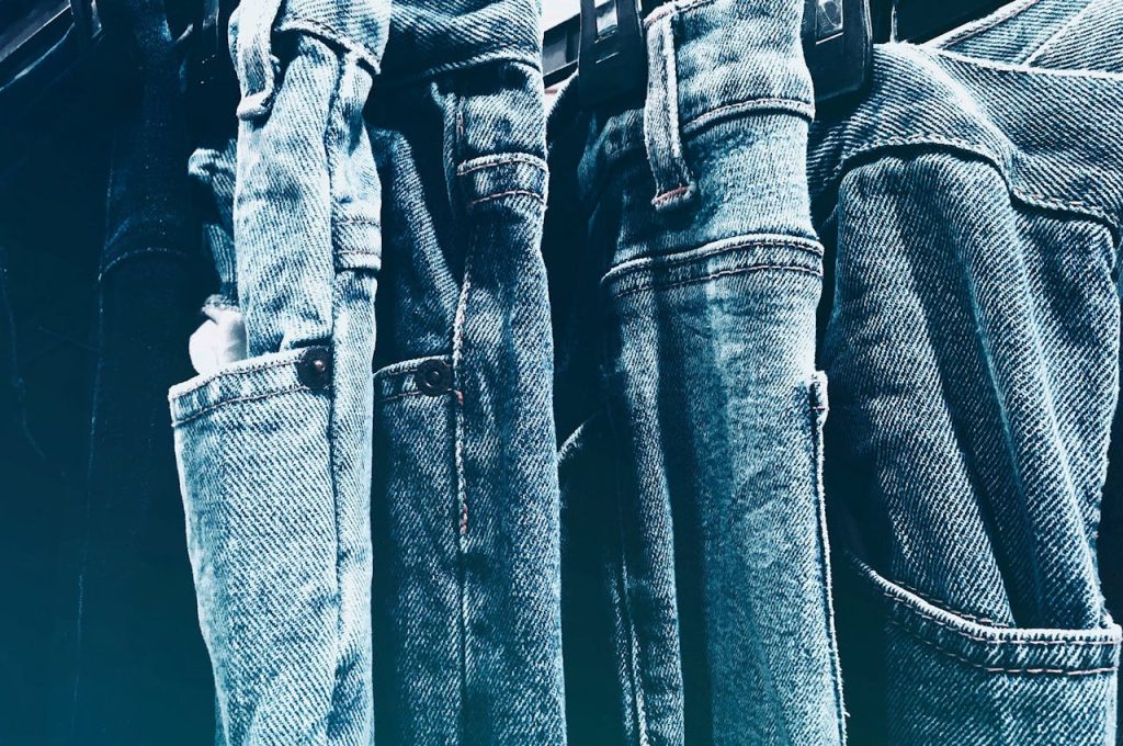 Close-up of worn denim jeans hanging, showing faded fabric texture and stitching