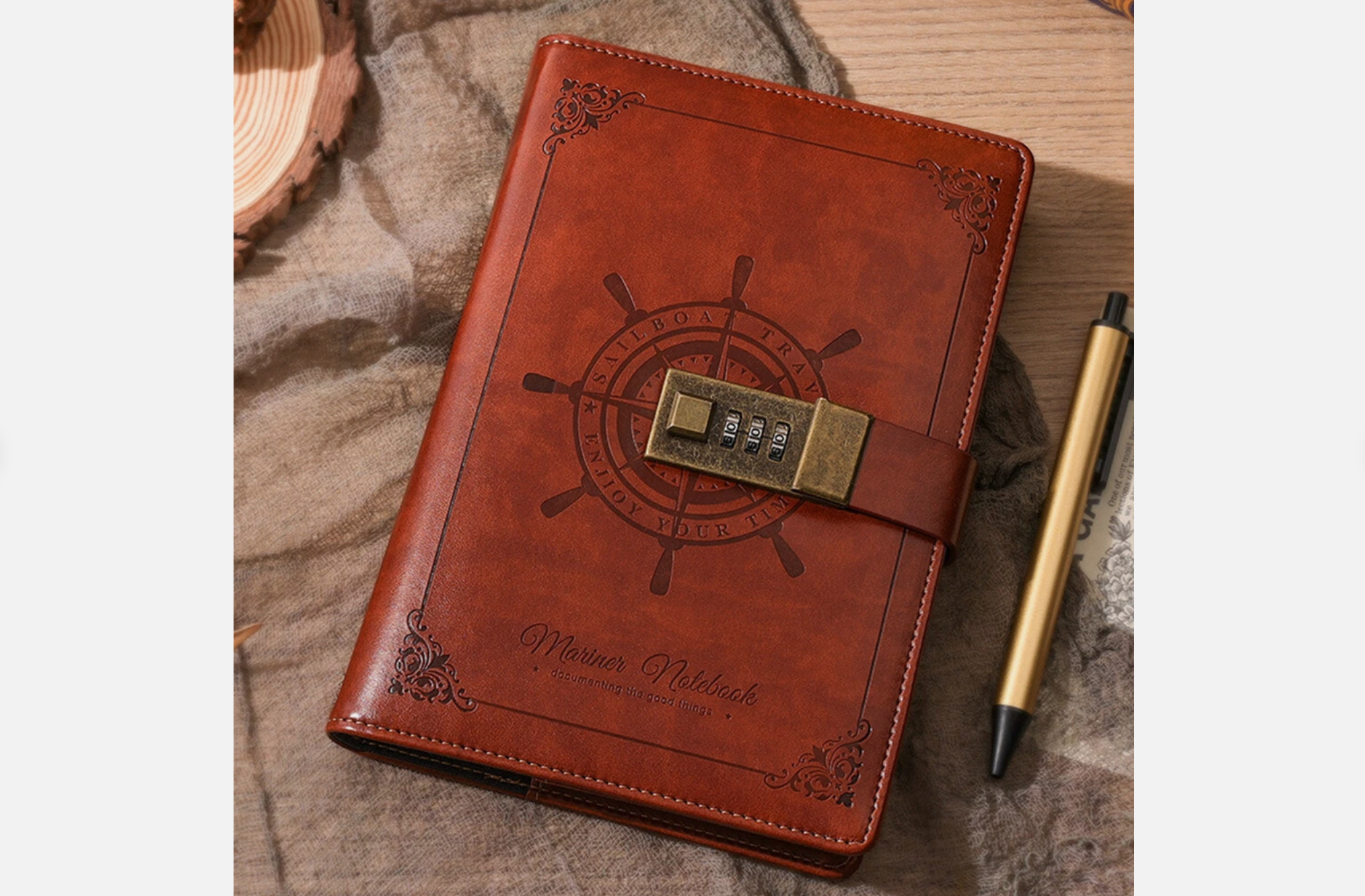 Brown leather-bound diary with embossed nautical design, secured by a brass combination lock, placed beside a gold pen on a rustic desk