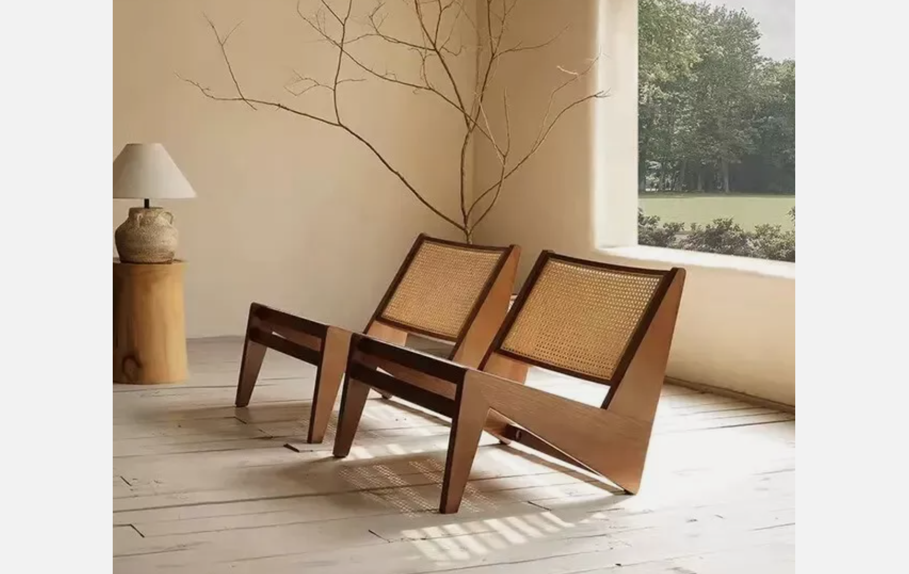 Pair of mid-century modern kangaroo chairs with wooden frames and woven rattan backs, placed in a minimal living space with light wood floors and soft natural light
