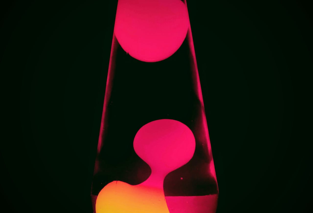 Close-up of a red lava lamp with glowing wax blobs suspended in liquid, set against a dark background