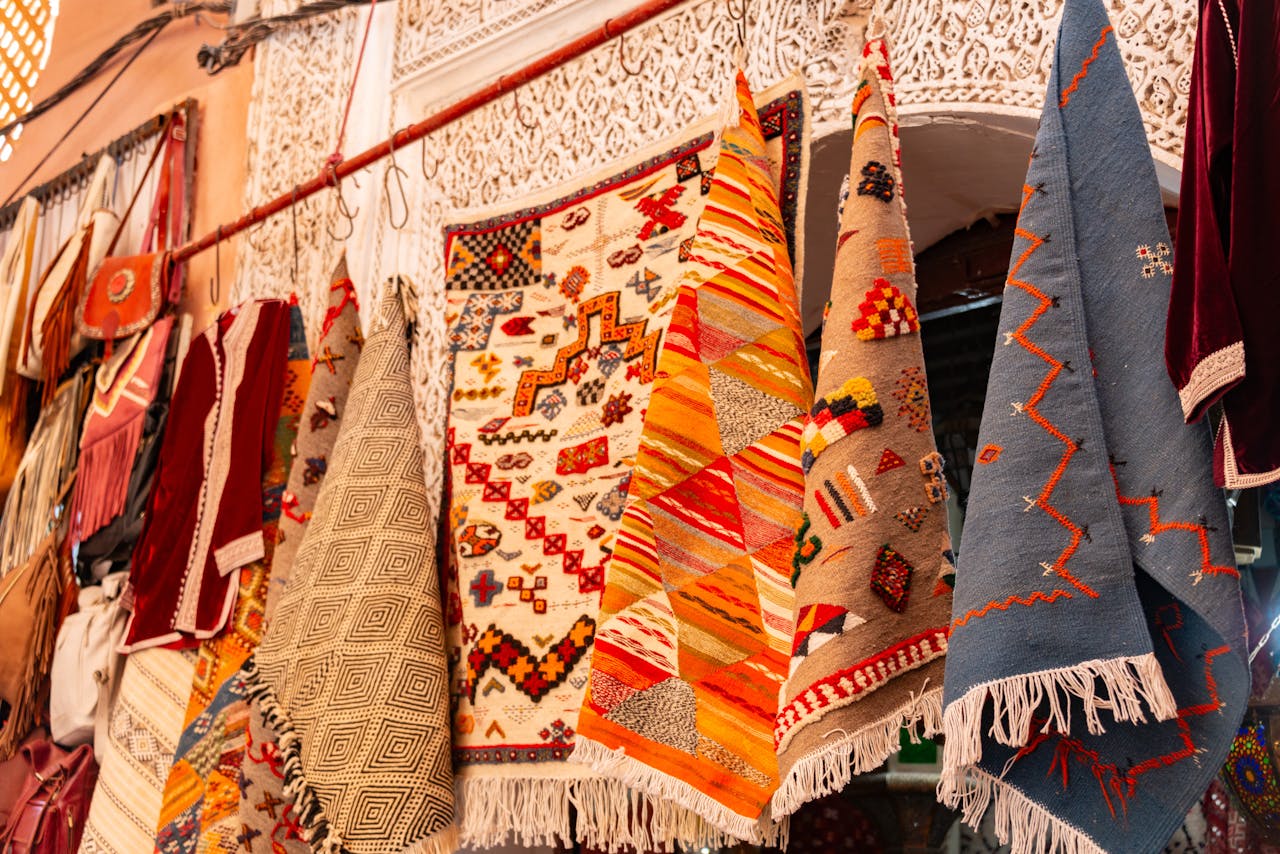 Colorful woven tapestries and rugs with geometric patterns hanging in a traditional market display