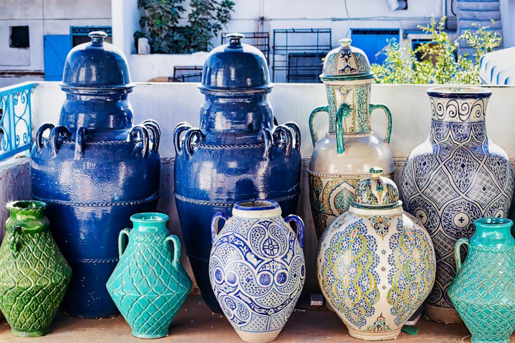 Collection of large ceramic vases in blue, green, teal, and cream, featuring intricate hand-painted patterns and embossed designs