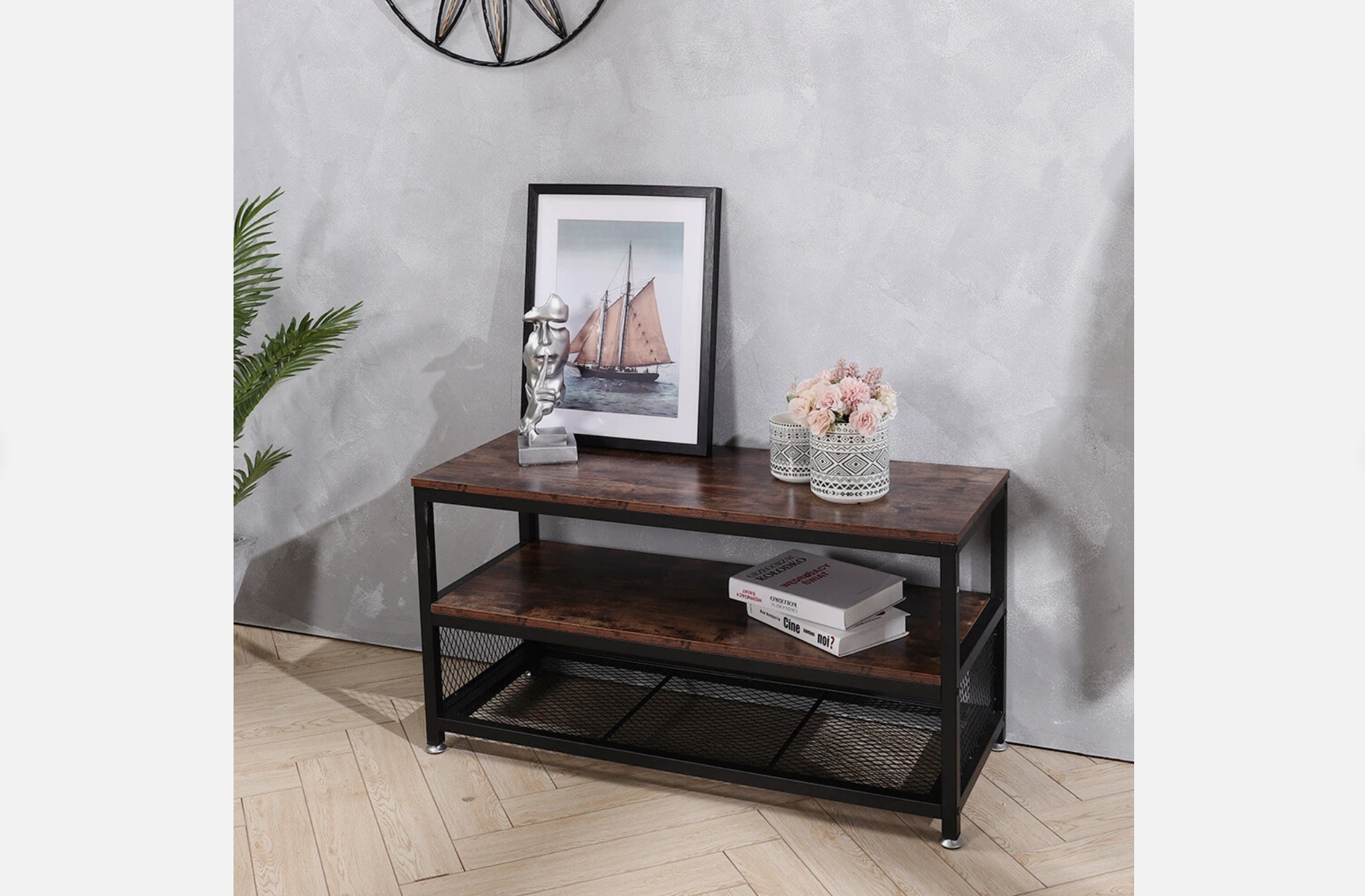 Rectangular wood and black metal coffee table, lower shelf with books, mesh bottom rack, decorated with framed art, silver sculpture