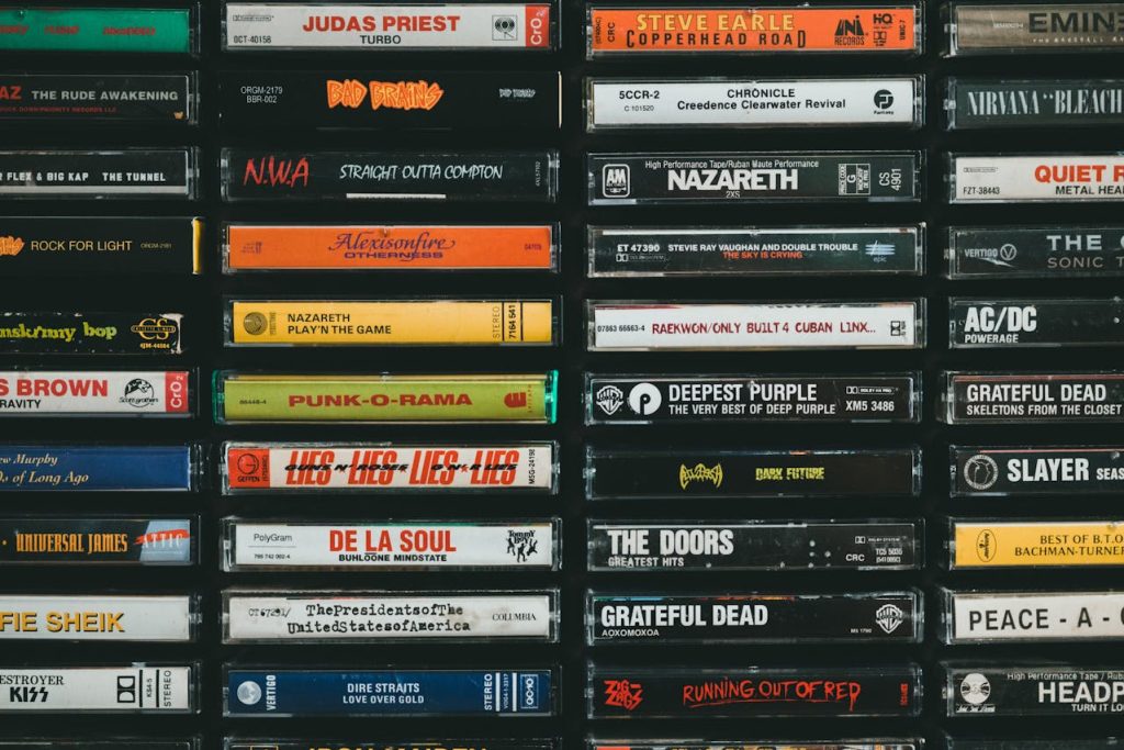 A large collection of labeled cassette tapes stacked in rows, spanning classic rock, hip-hop, and punk titles