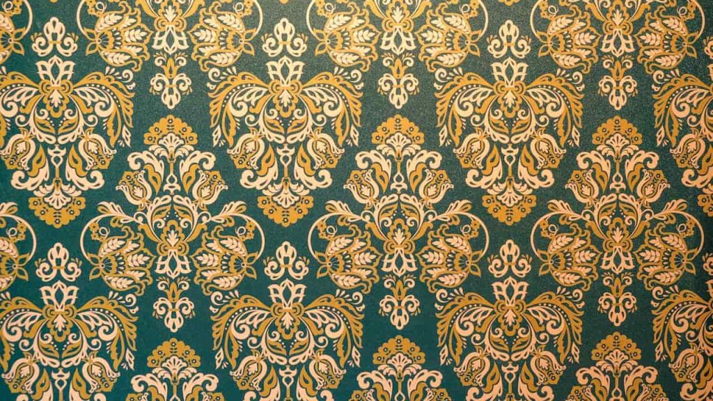 A richly detailed vintage wallpaper with an ornate damask pattern in gold and cream over a deep teal background, repeating symmetrically across the surface