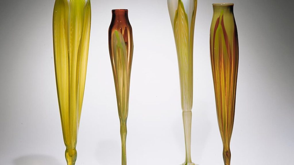 Four tall glass vases in gradient amber, ruby-red, and yellow tones, the kind of colored glass now being displayed inside china cabinets