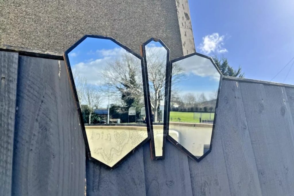 Angular, geometric Art Deco-style mirror panels catching light against an outdoor wall, evoking the chrome and brass accents driving the Neo Deco trend