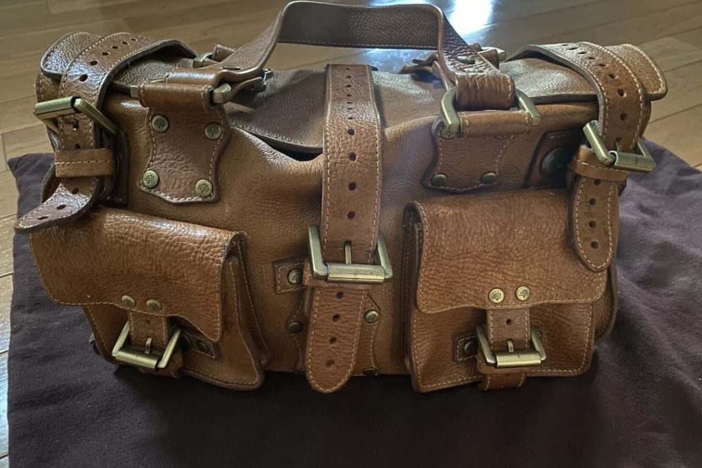 Structured dark brown leather handbag with buckled flap pockets and brass hardware, showing the kind of rugged, boxy construction and heavy hardware collectors look for in authentic vintage leather bags