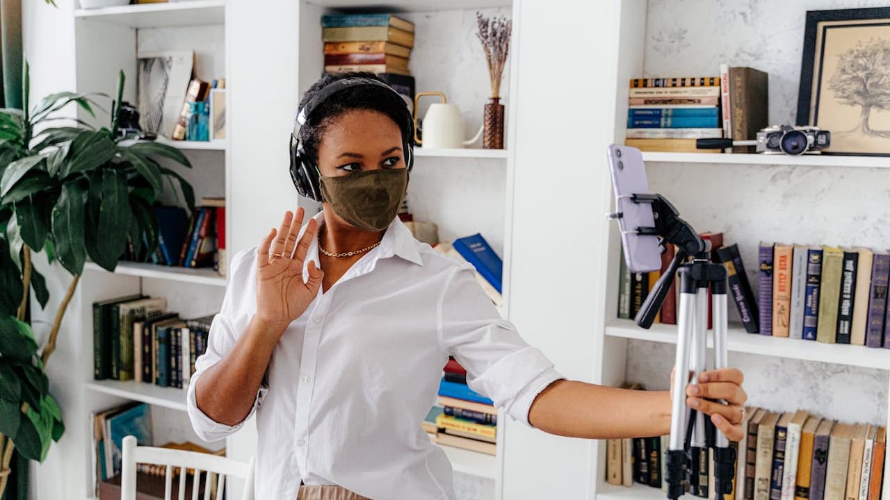 wearing a crisp white shirt, dancing indoors, surrounded by bookshelves and decor, posing with one arm raised, casual and expressive setting