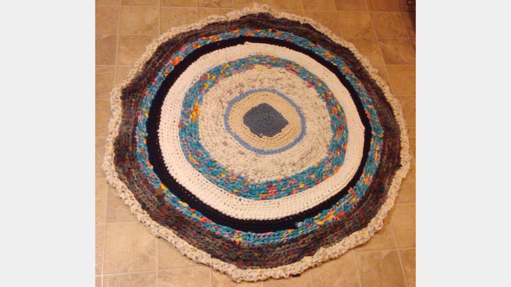 Rug constructed out of fabric strips cut from second use t-shirts and bed linens.