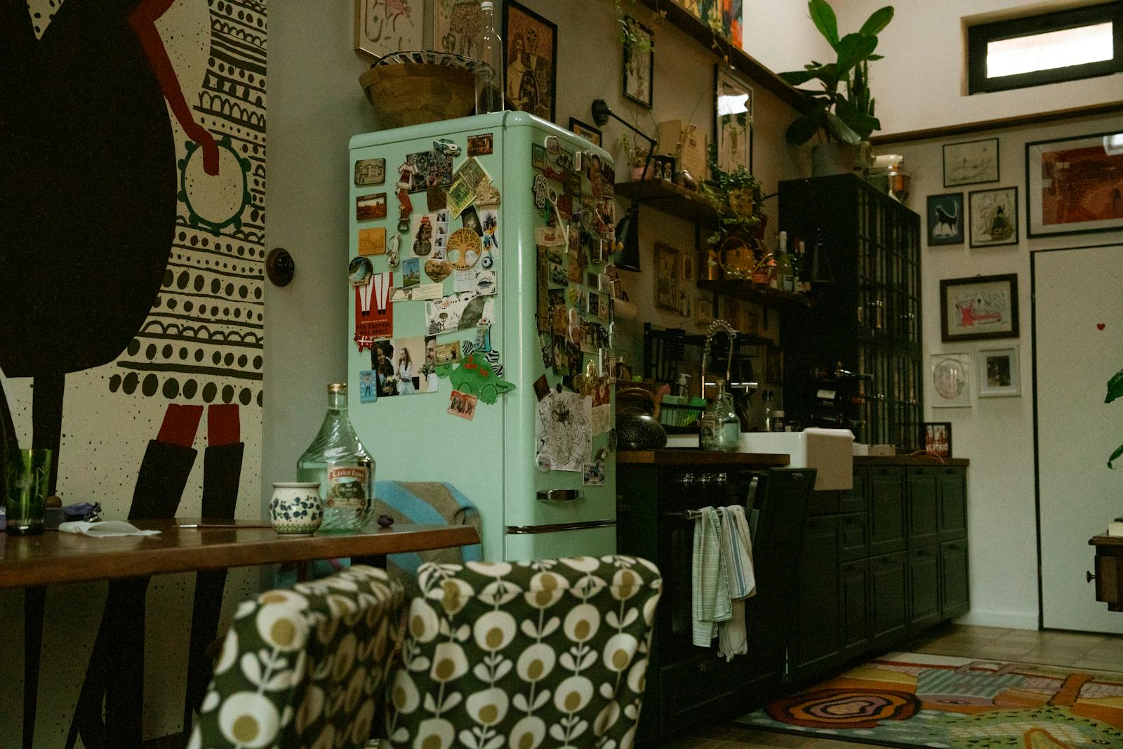 Stylish kitchen interior featuring retro fridge, vibrant art, and cozy, eclectic design elements.