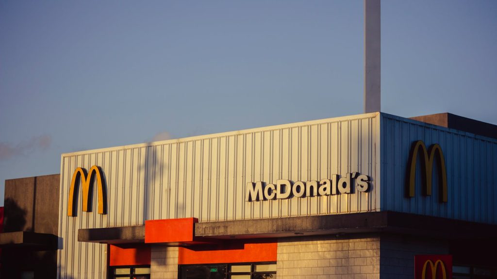 Photo of a McDonald's restaurant exterior under a clear sky, emphasizing its iconic architecture.