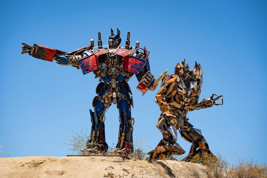 Metal sculptures resembling transformers under a bright blue sky in Aguanga, CA.