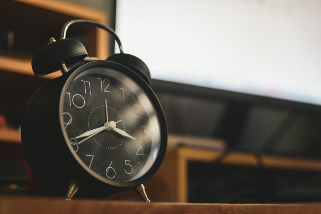 A black alarm clock on a wooden surface.