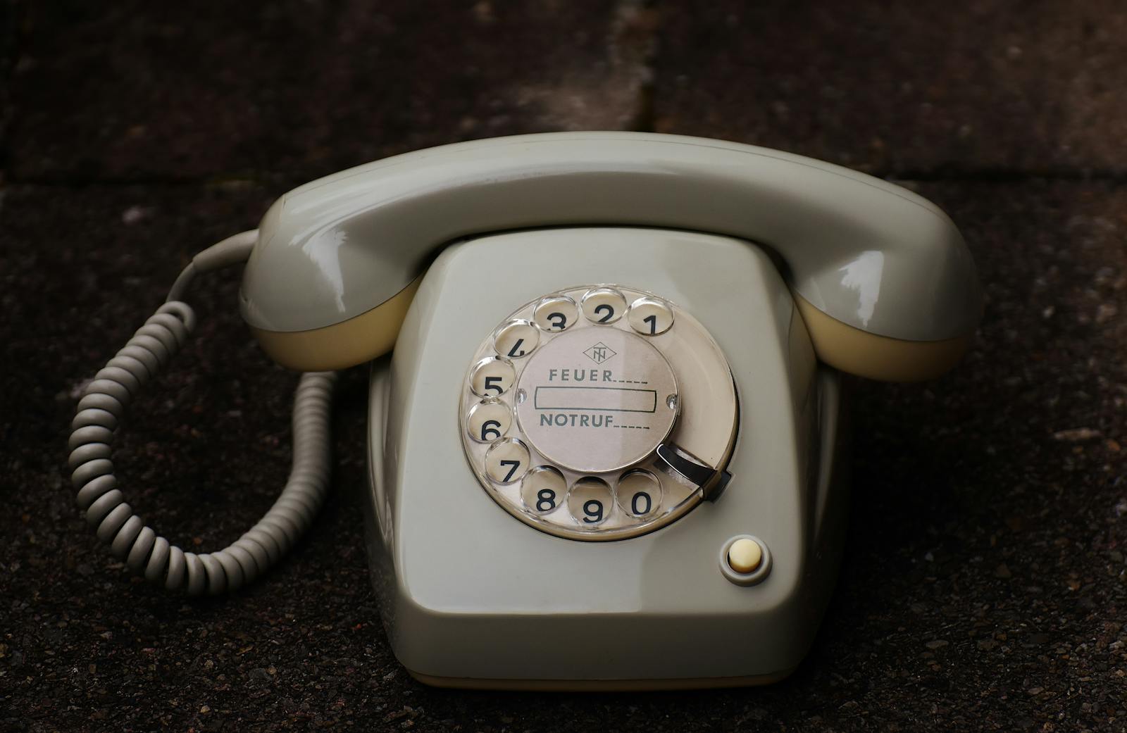 Close-up of an antique rotary phone on a dark surface, emphasizing retro technology.