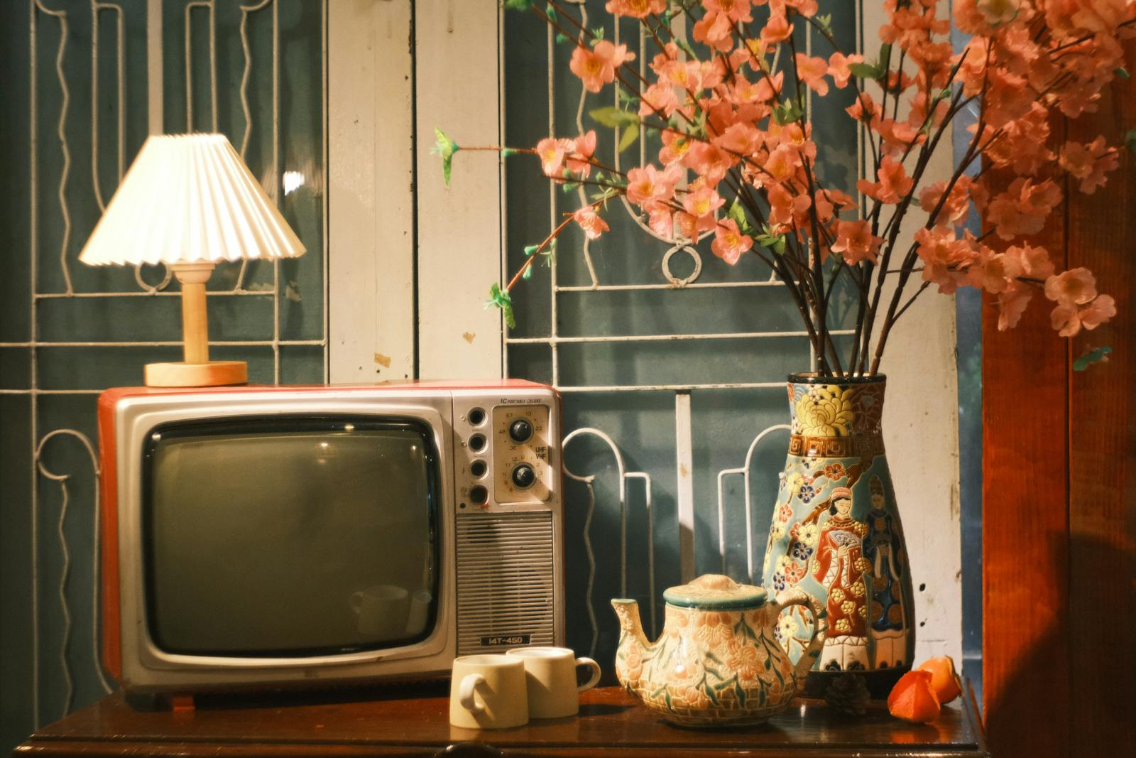A cozy vintage scene featuring a retro TV, a lamp, and cherry blossoms.