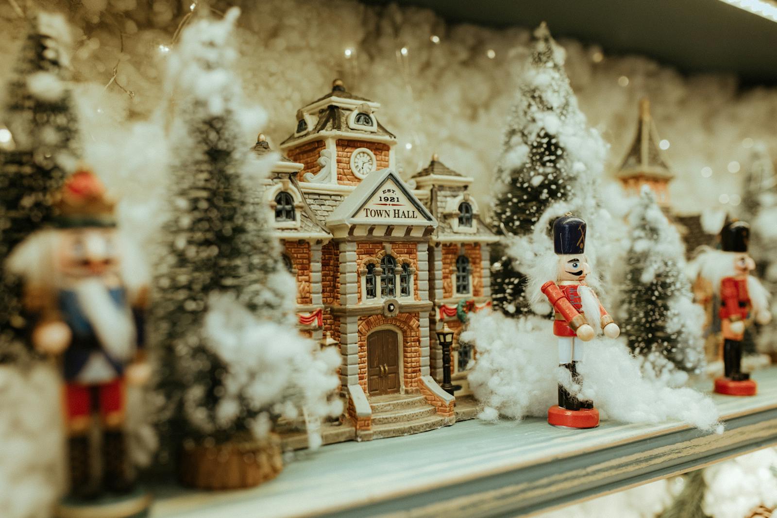 Charming miniature town hall scene with nutcrackers and snowy trees, evoking a festive holiday spirit.