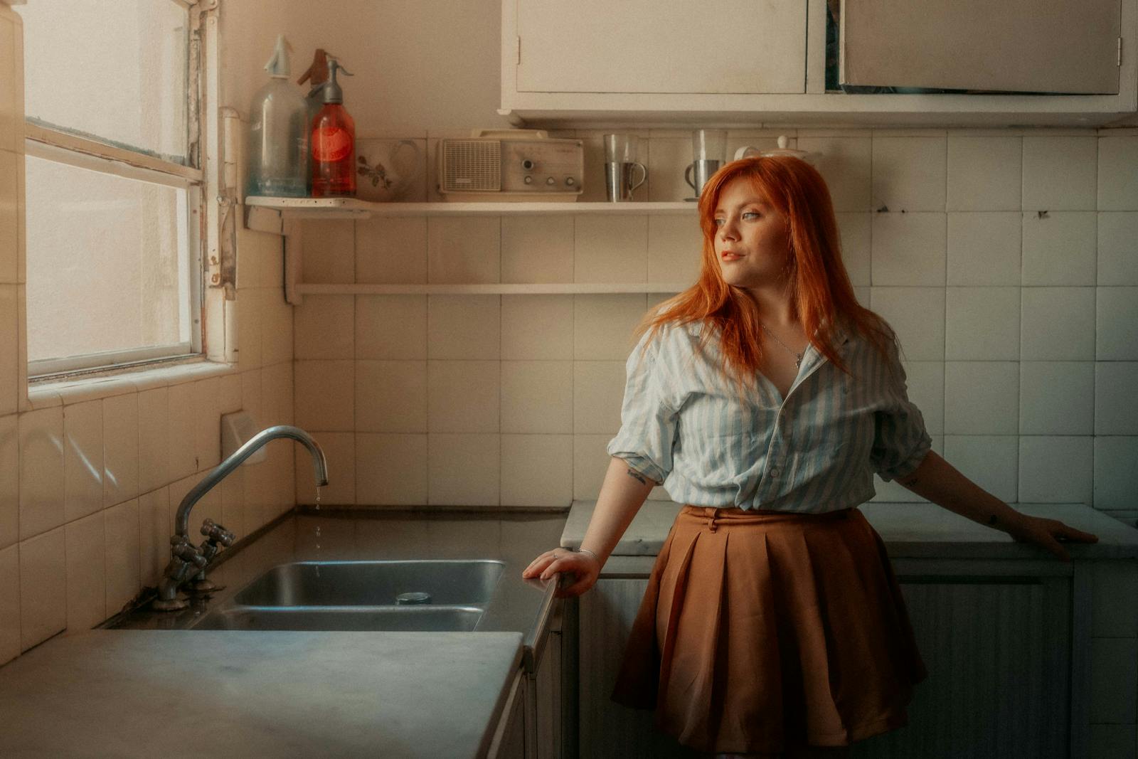 Contemplative woman in a vintage kitchen setting, bathed in warm light.