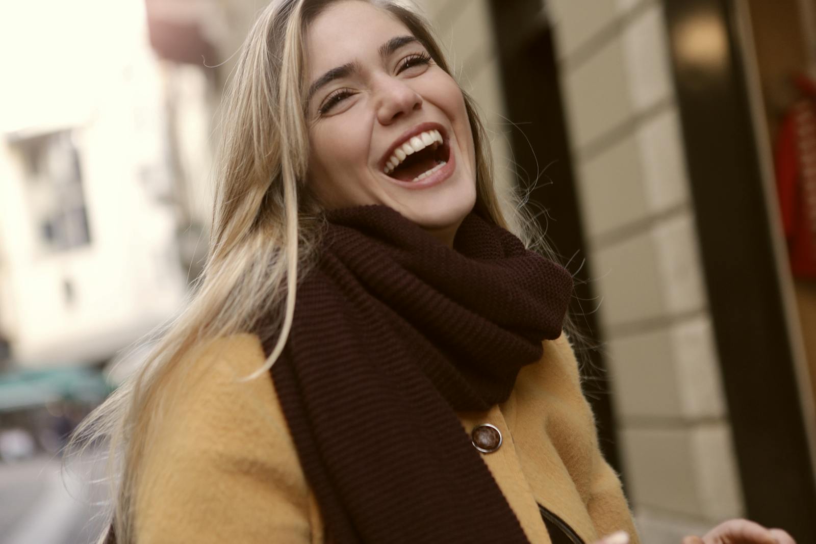 Vibrant portrait of a joyful woman laughing outdoors in winter clothing. Radiates happiness.