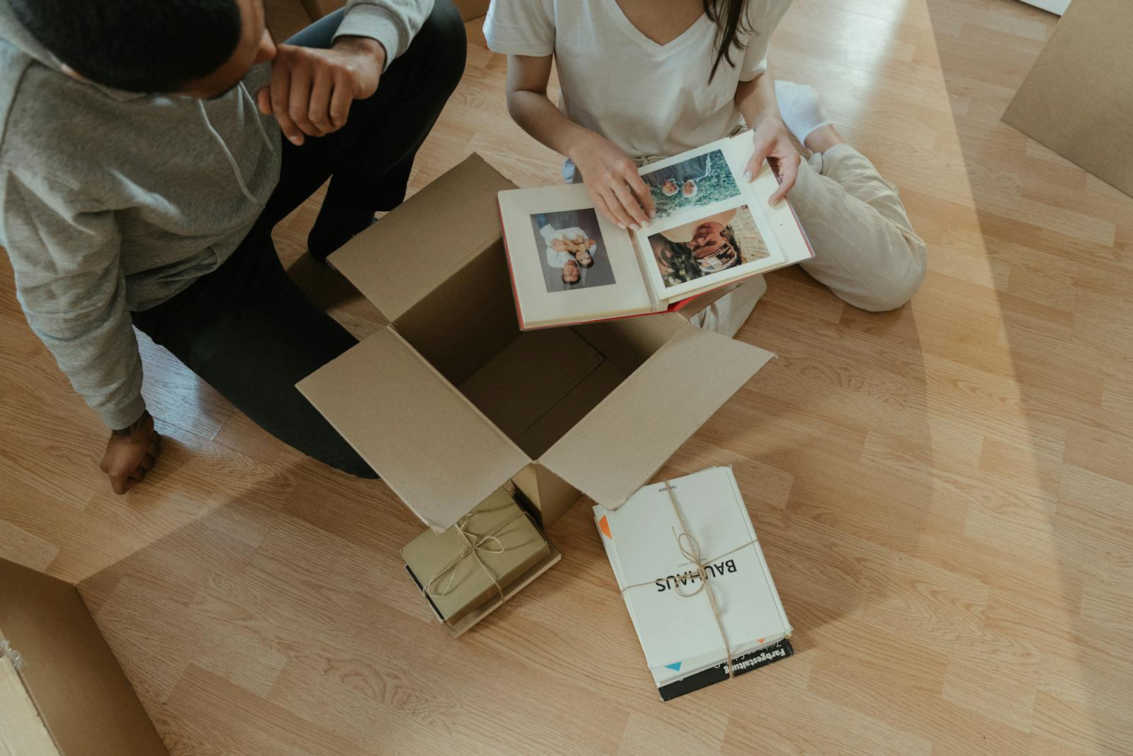 Couple going through photo albums while unpacking boxes in their new home.