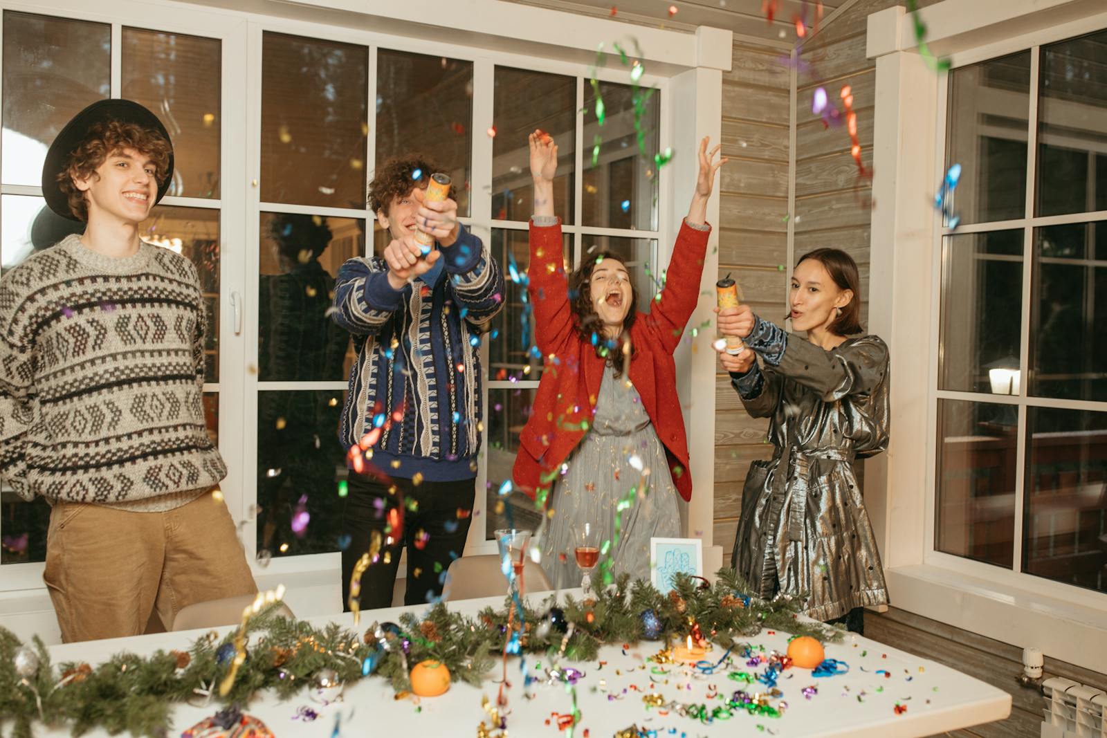 Group of young friends celebrating together with confetti indoors.