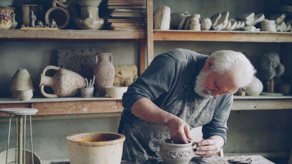 A potter works on a vase in his workshop.