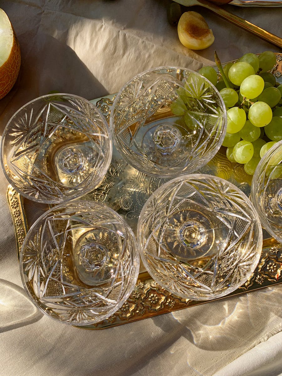 Crystal bowls with grapes on a gold serving tray, featuring a still life composition.
