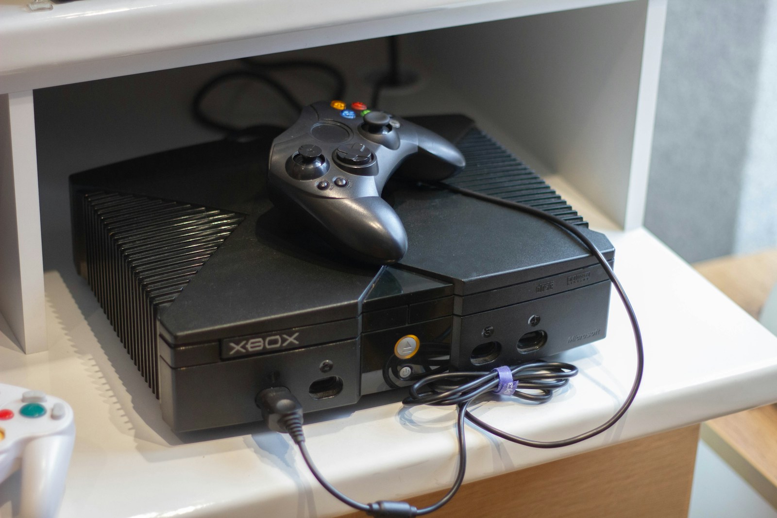 Here's a caption: an original xbox console with a controller.