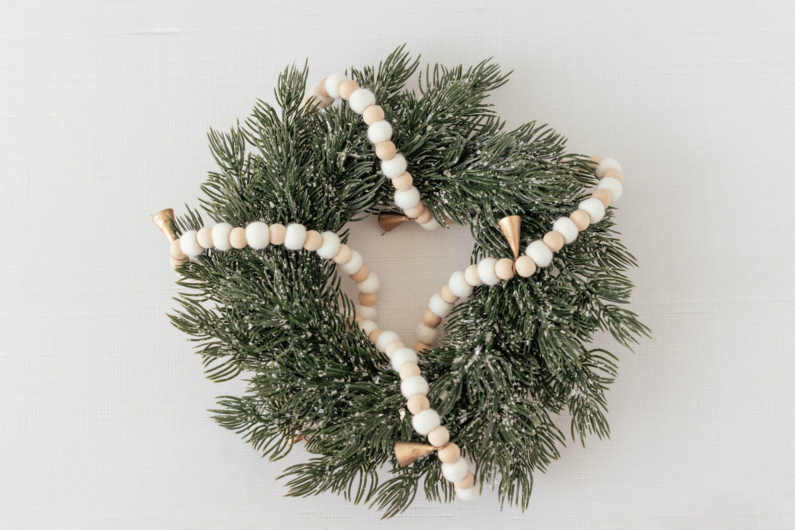 A green wreath with a beaded garland and bell garland
