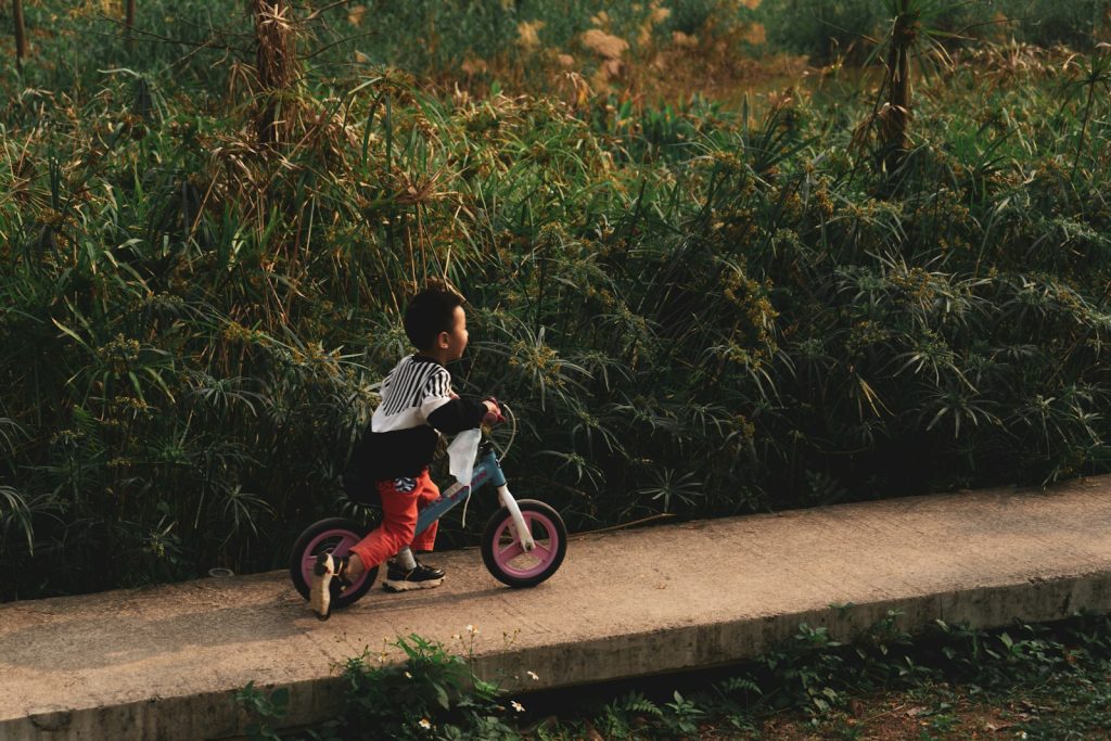 boy in black and white shirt riding on red and black trike