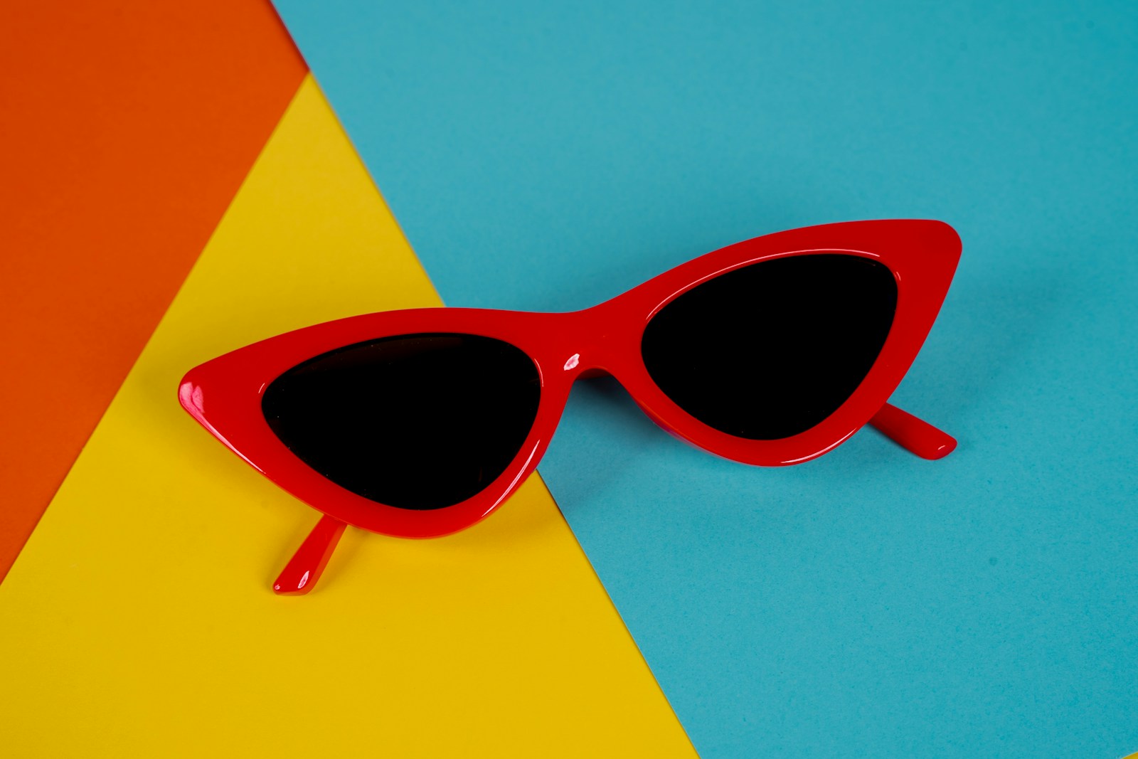 A pair of red sunglasses sitting on top of a blue and yellow background