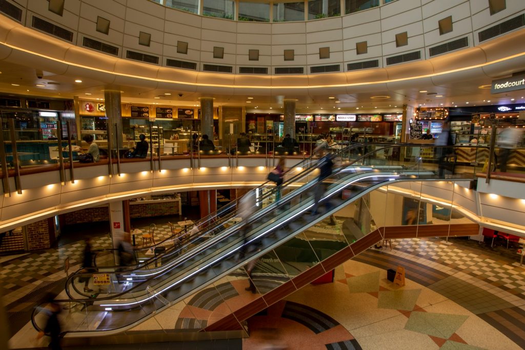 an escalator in a shopping mall with people walking down it