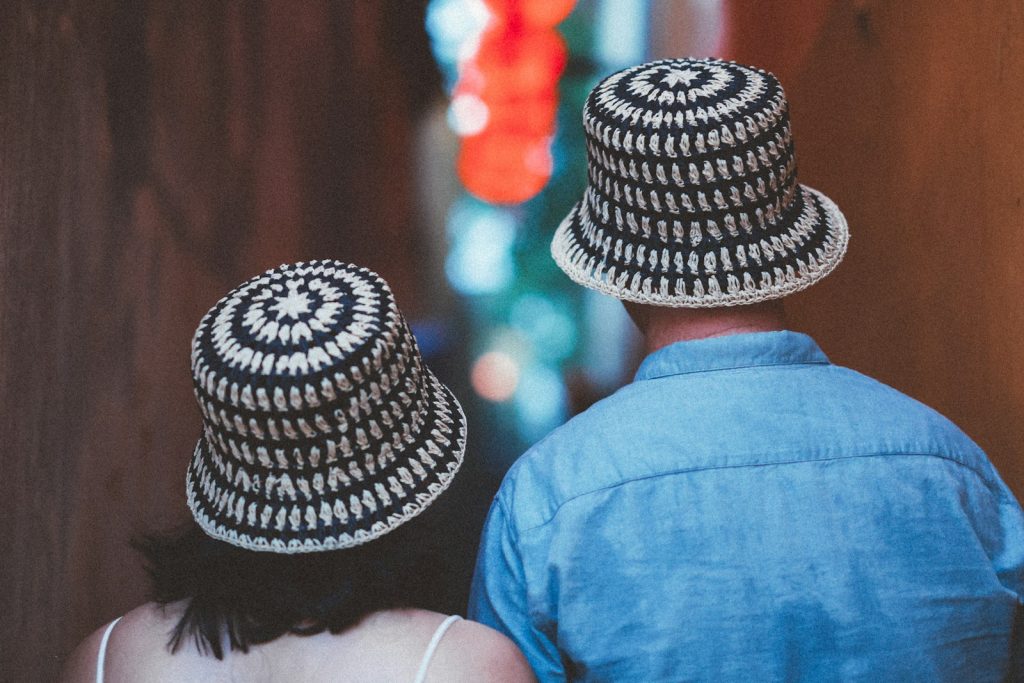 Two people wear matching patterned hats and walk away.