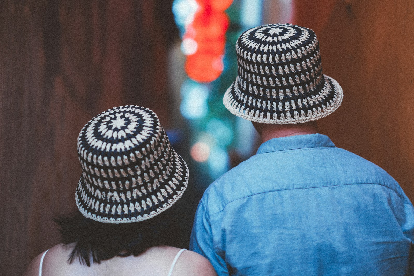 Two people wear matching patterned hats and walk away.