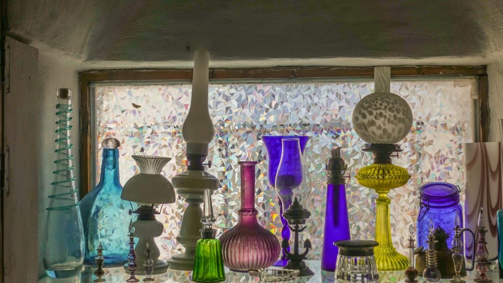 a collection of colorful glass vases sitting on a window sill