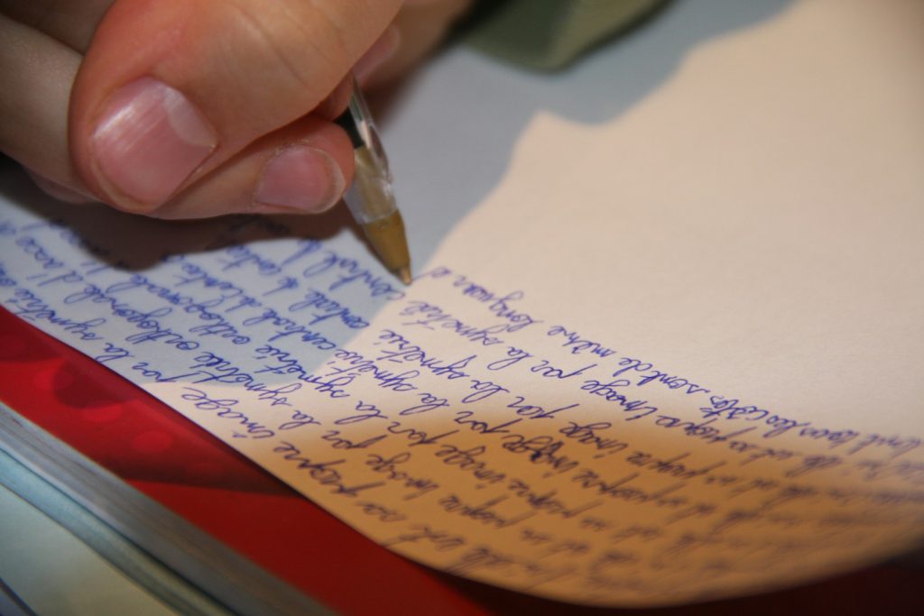 a person writing on a piece of paper with a pen