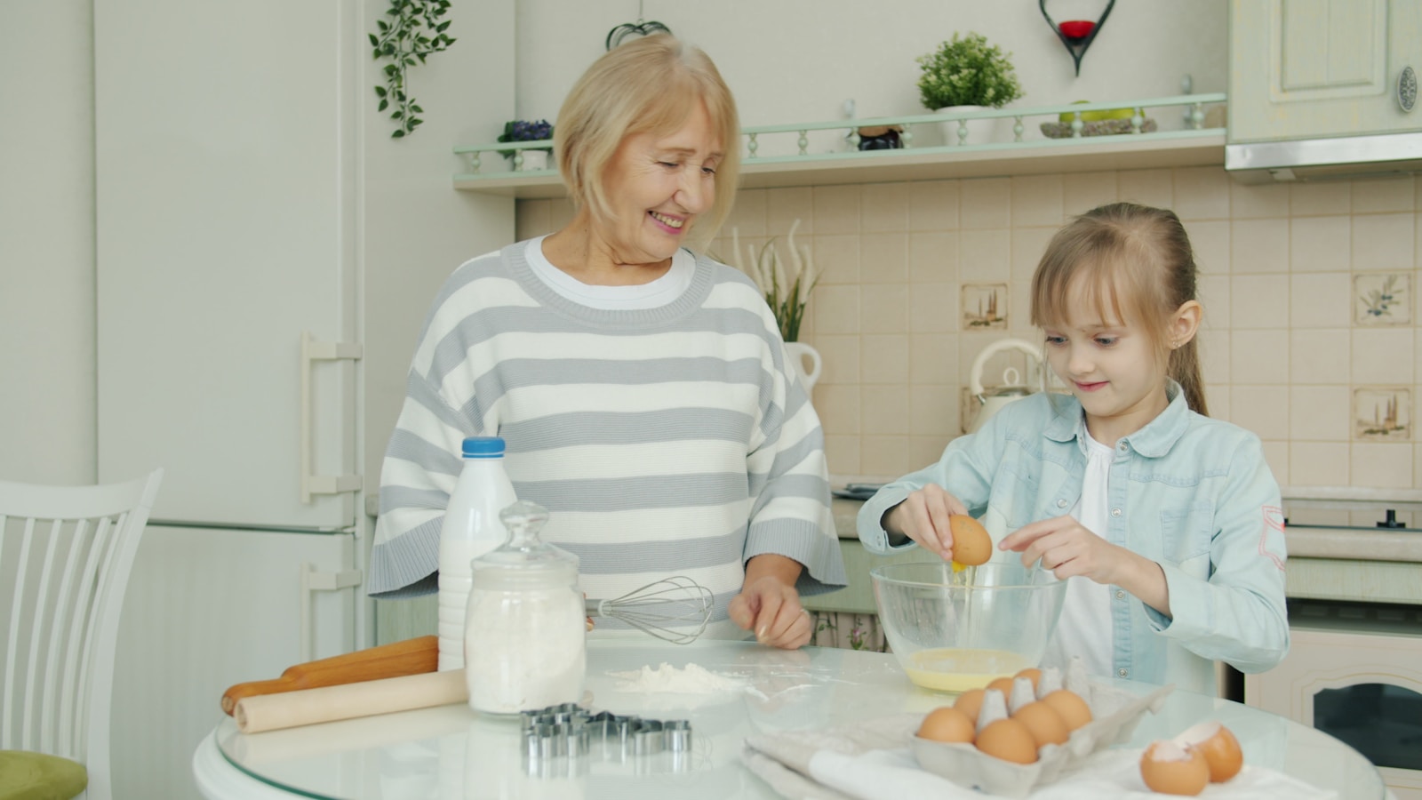Grandmother and granddaughter baking together in kitchen.