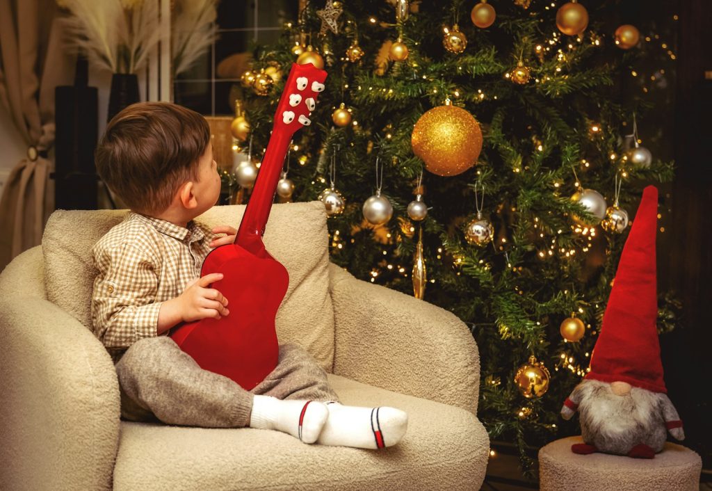 A little boy sitting in a chair next to a christmas tree