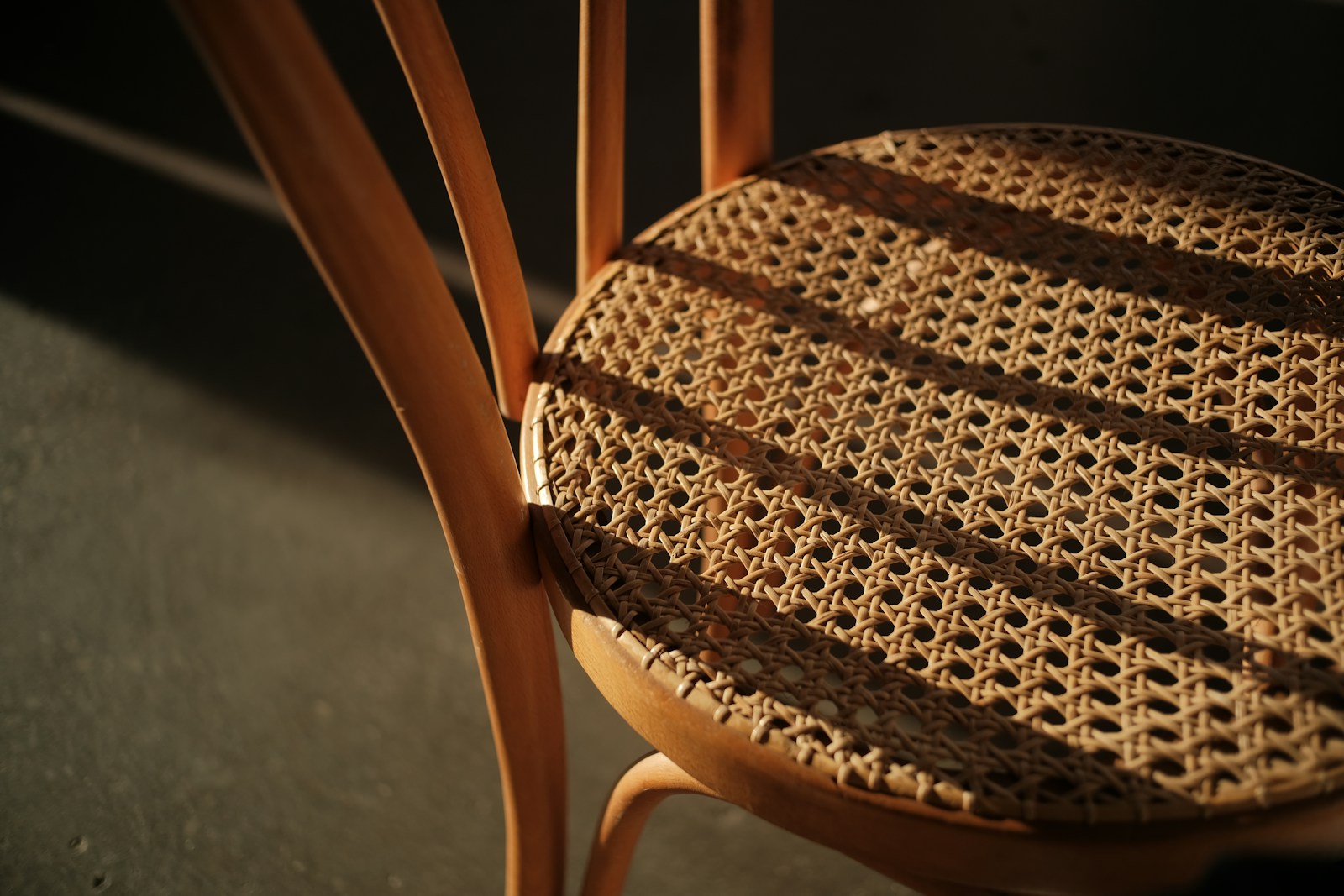 Woven seat of a wooden chair with striped shadows