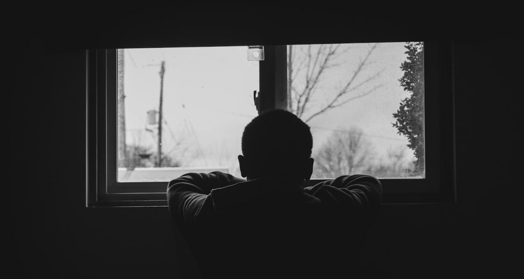 man in black and white stripe long sleeve shirt sitting on chair looking at the window