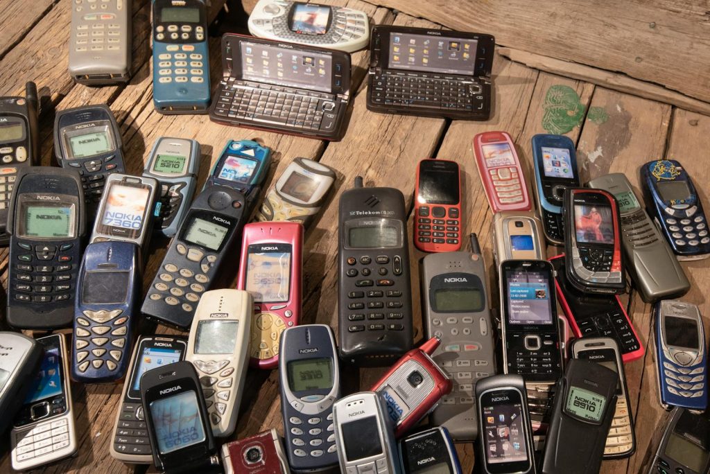 An assortment of retro mobile phones displayed on a rustic wooden surface, showcasing nostalgia.