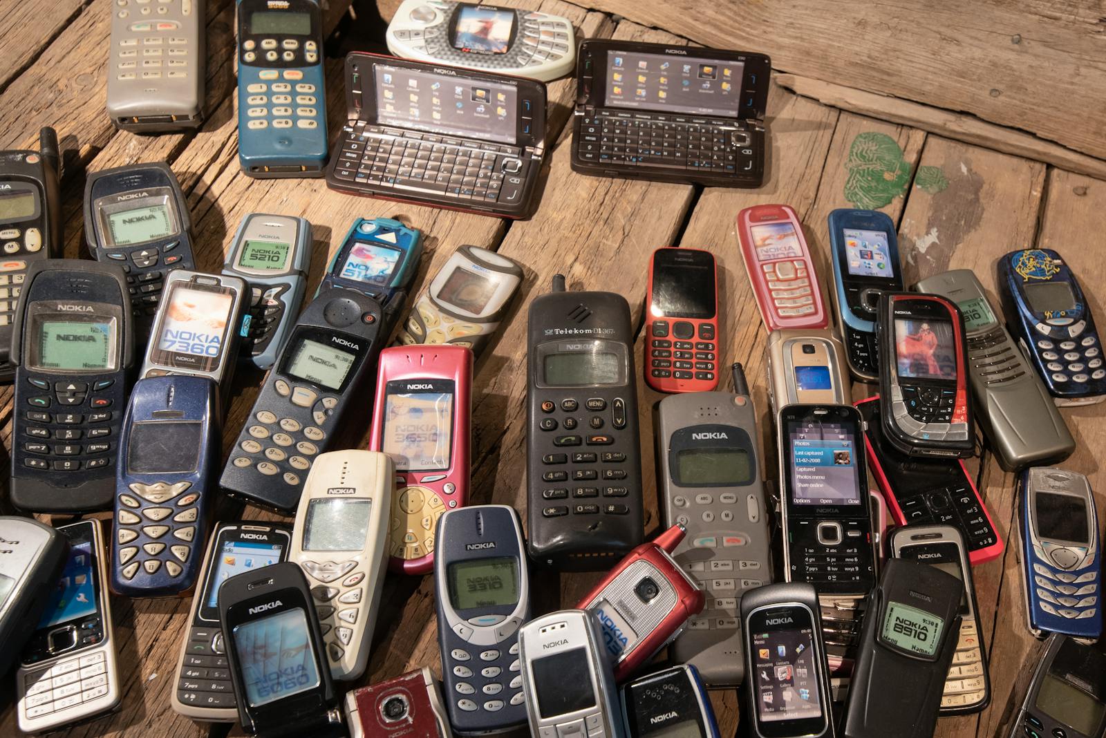 An assortment of retro mobile phones displayed on a rustic wooden surface, showcasing nostalgia.