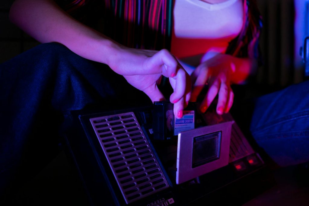 A woman adjusts a retro cassette player, highlighting vintage audio technology in a moody setting.
