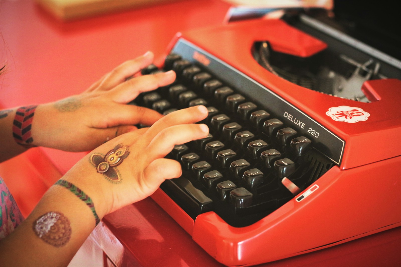 person holding red and black typewriter