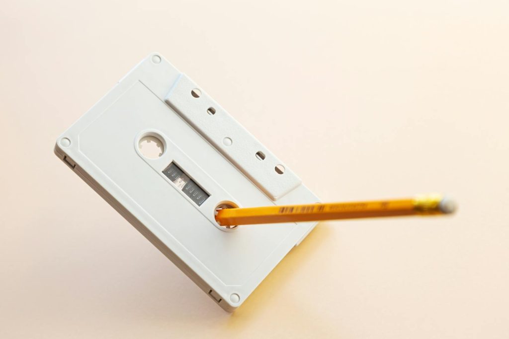 A vintage cassette tape with a pencil inserted, showcasing nostalgia and classic music storage.