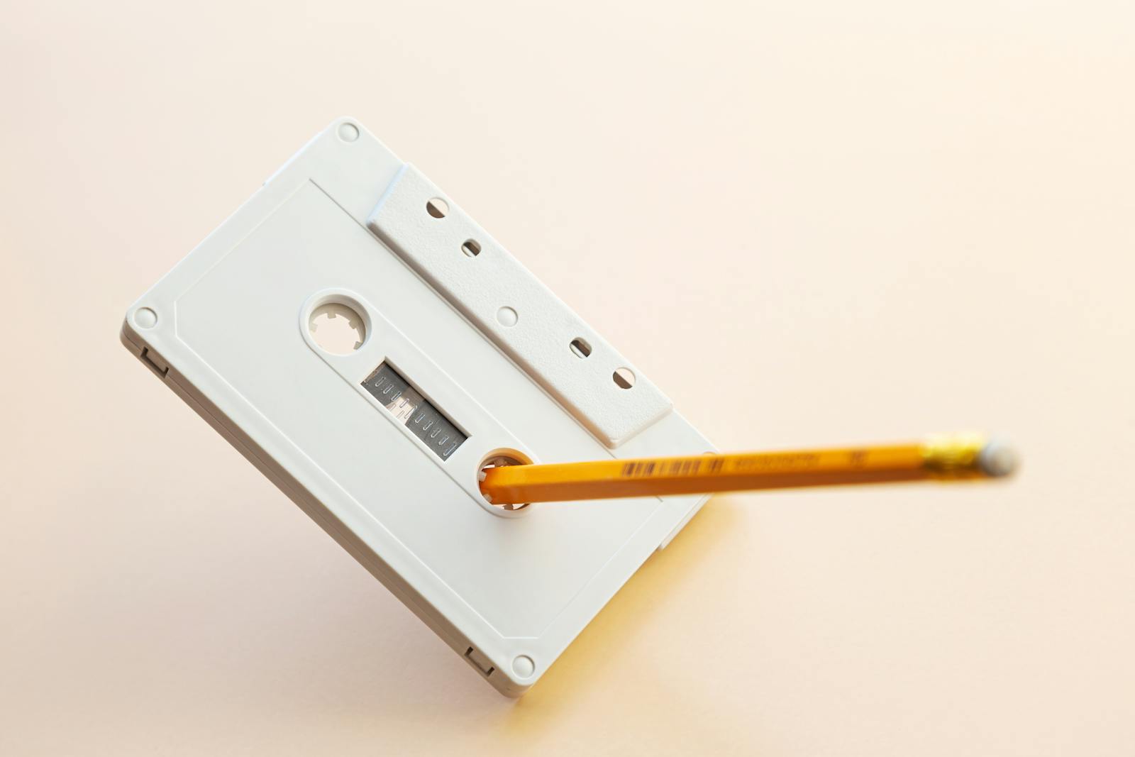 A vintage cassette tape with a pencil inserted, showcasing nostalgia and classic music storage.
