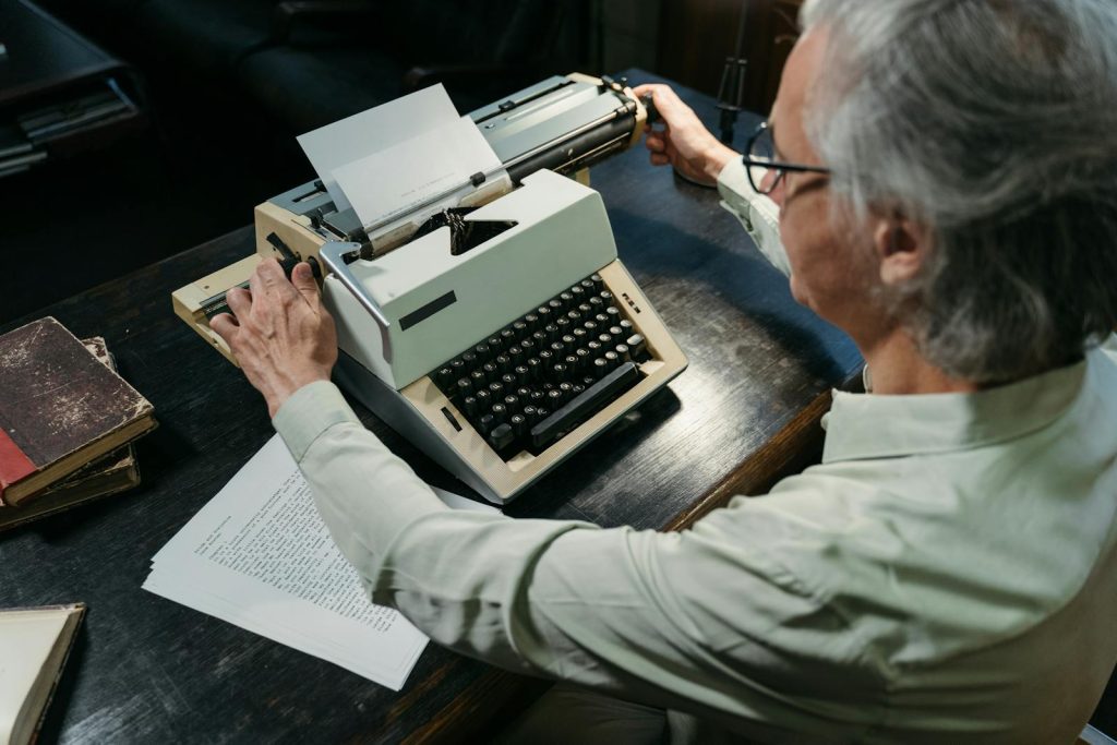 An adult man using a vintage typewriter in an office setting, capturing a timeless moment.