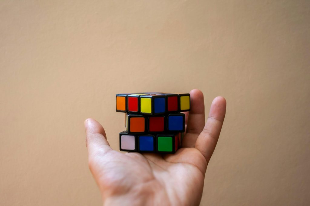 A hand holds a colorful, unsolved rubik's cube.