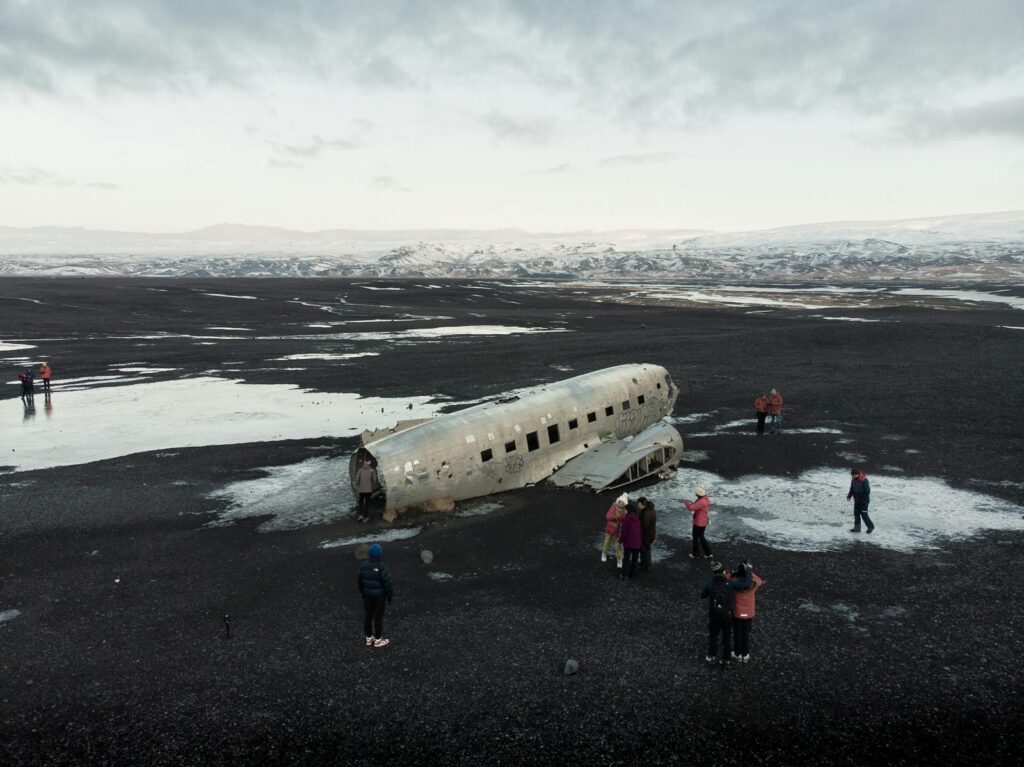 Tourists visit the famous airplane wreck on Iceland's black sand beach in winter.