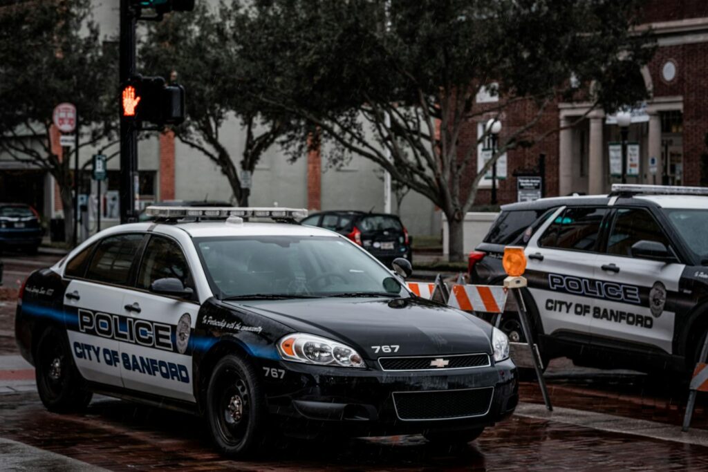 City of Sanford police cars parked on wet urban streets with traffic signals and buildings.